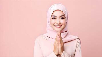 Southeast asian woman wearing scarf is praying and smiling on pink background photo