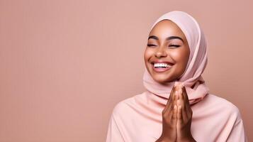 African woman wearing scarf is praying and smiling on pink background photo