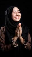 Southeast asian woman wearing scarf is praying and smiling on black background photo