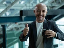 Businessman male gentleman person people human thumb up look at camera happy smile success wear suit shirt manager mature fashion skinhead manager business gesture copy space fashion ethnicity photo