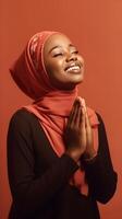 African woman wearing scarf is praying and smiling on red background photo