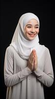 Southeast asian woman wearing scarf is praying and smiling on black background photo