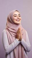 European woman wearing scarf is praying and smiling on purple background photo