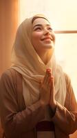 Southeast asian woman wearing scarf is praying and smiling on brown background photo