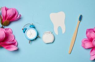 Dental floss and paper teeth on blue background, oral hygiene photo