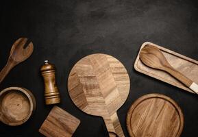 Various wooden kitchen utensils on black background, top view. photo