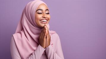 African woman wearing scarf is praying and smiling on purple background photo
