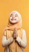 Southeast asian woman wearing scarf is praying and smiling on orange background photo