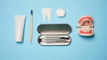 Mouthwash, toothpaste tube, dental floss and medical mirror on a blue background, oral hygiene. photo