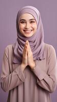 Southeast asian woman wearing scarf is praying and smiling on purple background photo