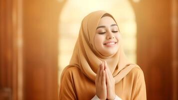 Southeast asian woman wearing scarf is praying and smiling on orange background photo