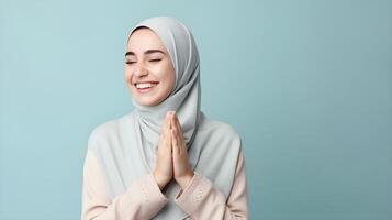 Southeast asian woman wearing scarf is praying and smiling on blue background photo