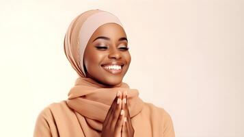 africano mujer vistiendo bufanda es Orando y sonriente en blanco antecedentes foto