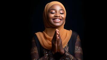 africano mujer vistiendo bufanda es Orando y sonriente en negro antecedentes foto