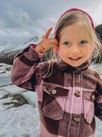 Funny little girl in blue winter clothes walks during a snowfall. photo