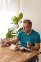 Seniory man checks blood pressure with monitor on upper arm in room photo