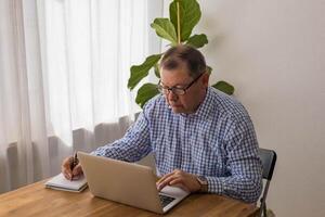 Senior man working on laptop in the home photo