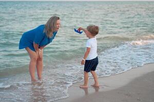 Mother son spending time together sea vacation Young mom child little boy walking beach photo