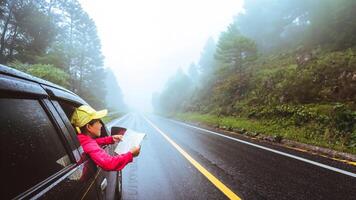 las mujeres asiáticas viajan relajadas en las vacaciones. viajar en aparcamiento. ver mapa para recorridos por la naturaleza durante la temporada de lluvias. foto