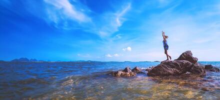 Asian women relax in the holiday. Travel relax. Play if yoga. On the rocks by the sea. In the summer. Thailand photo