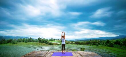 mujer asiática relajarse en las vacaciones. jugar si yoga. en el balcón paisaje campo natural foto