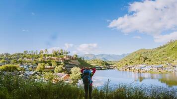 Girl with backpack stand looking forward on beautiful view in lake. Tourist traveler looking sunlight on mountains. Tea plantation in Mae Hong Son. photo