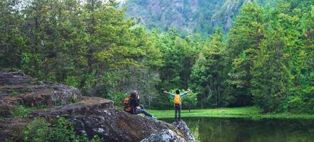 Couple sitting on rocks and taking pictures nature, flowers. at Paphiopedilum orchid conservation center. photo