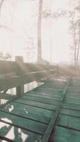 Suspended wooden bridge crossing the river to foggy mysterious forest video