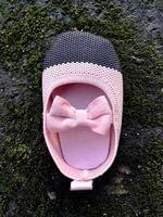 Cute little baby shoes pink and black color on plaster and moss plants background photo