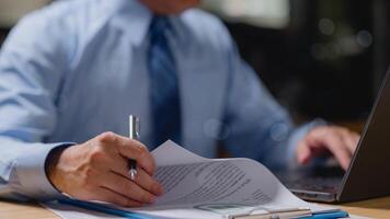 Businessman manager is sitting at a desk with a laptop and a pen. He is writing on a piece of paper photo