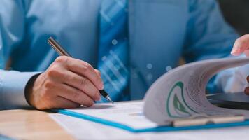 Marketing manager is writing on a piece of paper with a pen. He is wearing a blue shirt and a tie. Concept of professionalism and focus, as the man is engaged in a task that requires concentration photo