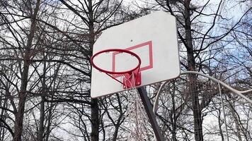 een basketbal hoepel in de werf met een gescheurd netto. het werpen de bal in de hoepel video