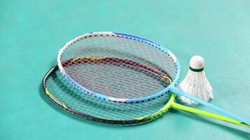 White badminton shuttlecocks and badminton rackets on green floor indoor badminton court soft and selective focus on shuttlecocks and the rackets photo