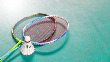 White badminton shuttlecocks and badminton rackets on green floor indoor badminton court soft and selective focus on shuttlecocks and the rackets photo