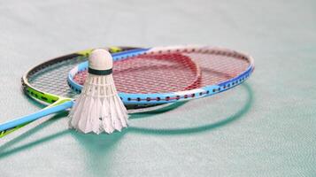 White badminton shuttlecocks and badminton rackets on green floor indoor badminton court soft and selective focus on shuttlecocks and the rackets photo