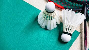 White badminton shuttlecocks and badminton rackets on green floor indoor badminton court soft and selective focus on shuttlecocks and the rackets photo