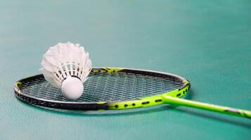 White badminton shuttlecocks and badminton rackets on green floor indoor badminton court soft and selective focus on shuttlecocks and the rackets photo