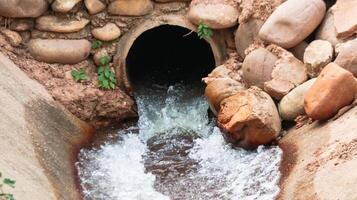 Water flowing out of concrete pipe in concrete canal photo