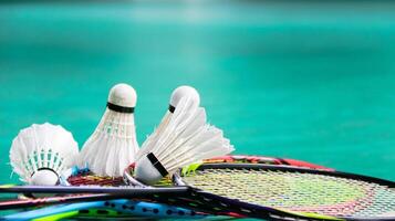 White badminton shuttlecocks and badminton rackets on green floor indoor badminton court soft and selective focus on shuttlecocks and the rackets photo