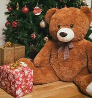 Teddy bear near christmas tree with gifts photo