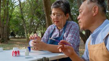 A group of Asian senior people enjoy painting cactus pots and recreational activity or therapy outdoors together at an elderly healthcare center, Lifestyle concepts about seniority photo