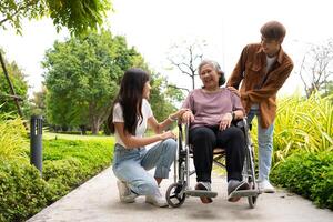 Asian careful caregiver or nurse taking care of the patient in a wheelchair. Concept of a happy retirement with care from a caregiver and Savings and senior health insurance, a Happy Family photo