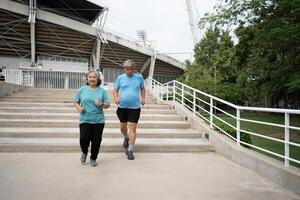 contento y sonrisa parejas mayor asiático corriendo en escalera para ejercicio, trotar en mañana, mayor ejercicio al aire libre para bueno saludable. concepto de cuidado de la salud y activo estilo de vida para sano foto