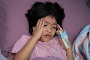 un pequeño asiático niña tiene un oxígeno máscara y respiración mediante un nebulizador a el hospital. concepto de bronquitis, respiratorio y médico tratamiento, inhalando medicamento, neblina, desde un nebulizador. foto