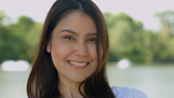 Happy smiling pretty Asian woman with a smile on her face looking at the camera in broad daylight in the park, natural sunlight, portrait sensation of an Asia girl. photo