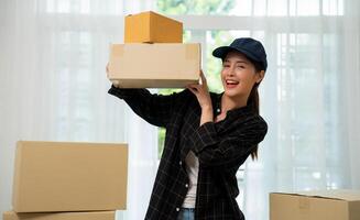 Smiling young woman holding cardboard box, Online shopping delivery concept. Online marketing and delivery. Young asian girl holding and carrying brown boxes for shipping to the client. photo