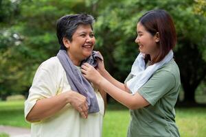 Attractive Senior mother and daughter working out together in the morning exercise in the park. Daughter absorbs sweat from her mom with white towel, a senior caregiver, and a happy family concept. photo