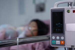 A little Asian girl has an oxygen mask and breathing through a nebulizer at the hospital. Concept of bronchitis, respiratory and Medical treatment, inhaling medicine, mist, from a nebulizer. photo