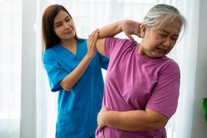 un joven asiático mujer fisioterapeuta enfermería es ayudando un mayor mujer ejercicio extensión músculos a hogar o un prima clínica para recuperación, concepto de físico terapia. foto