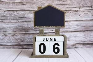 Chalkboard with June 06 date on white cube block on wooden table. photo